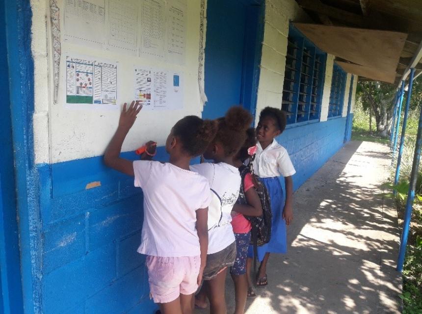 School children reviewing the Vanuatu Climate Update (VCU) placed on community and school notice boards. 